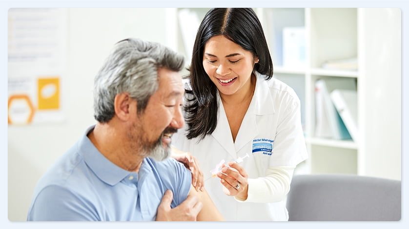 A Walmart pharmacist giving a flu shot to a smiling patient